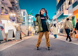 woman in green jacket stands and pose on street