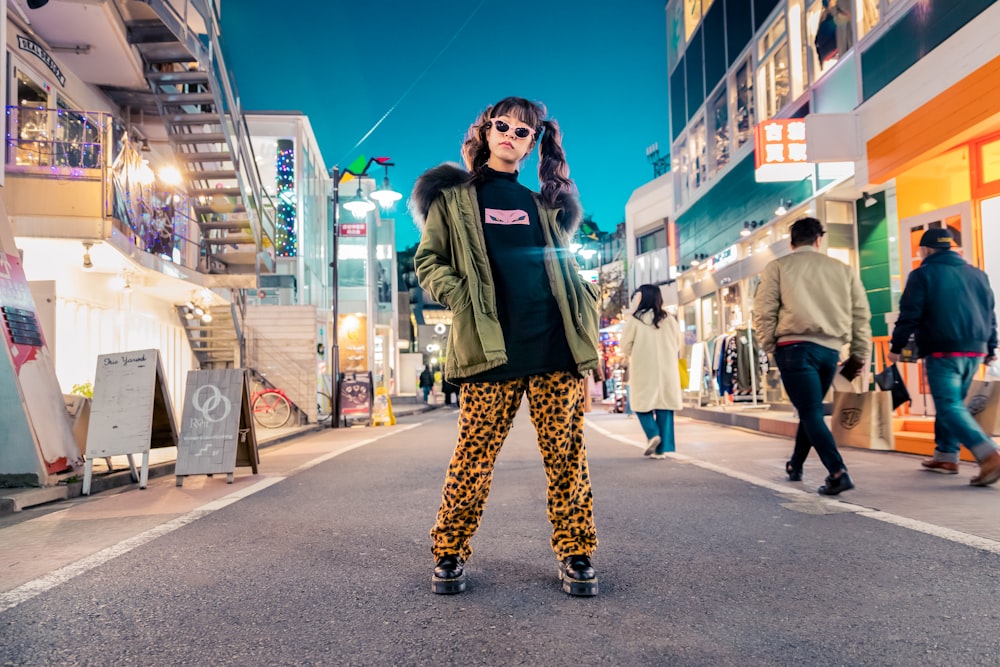 Femme en veste verte se tient et pose dans la rue