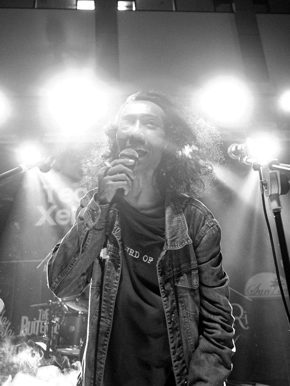 grayscale photography of man singing and performing on stage