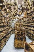 A store filled with numerous wooden items displayed on shelves and hanging from the ceiling. The assortment includes spoons, bowls, cutting boards, and various kitchen utensils made from wood. The arrangement creates a dense and rustic atmosphere.