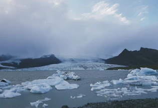 A serene black and white photograph of an iceberg floating in Disko Bay under soft, diffused light.