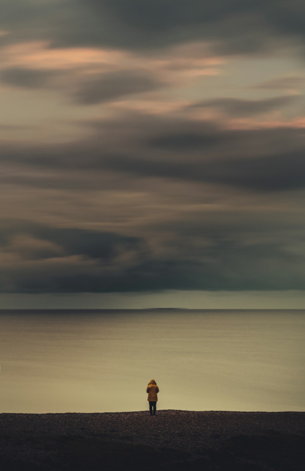 person standing and facing calm sea