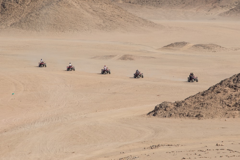 five people riding ATV's in desert