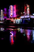 A lively street scene with neon lights illuminating a popular stripclub entrance.