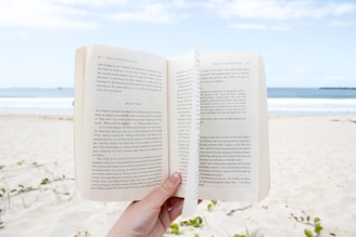 A happy customer holding a Beachy Books cookbook while standing on a sunny beach.