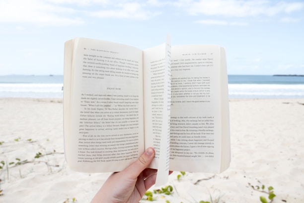 A happy customer holding a Beachy Books cookbook while standing on a sunny beach.