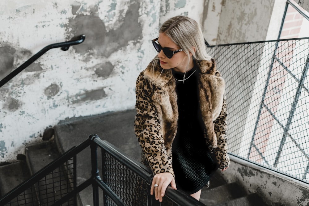 woman in black and brown animal print coat walking on stairs