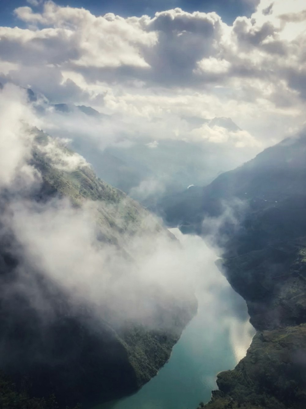 river beside mountains under grey clouds