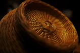 Close-up of hands weaving straw into a decorative basket.