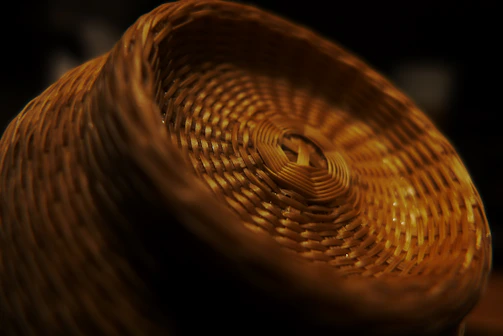 Close-up of hands weaving straw into a decorative basket.