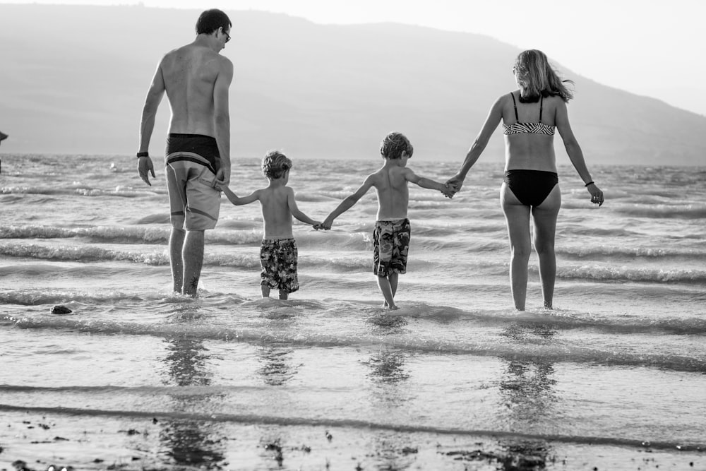 ビーチを歩く家族のグレースケール写真
