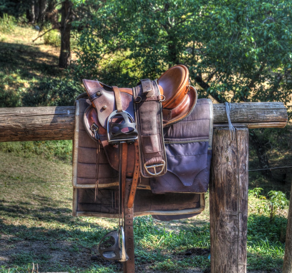 柵の上の茶色の革の馬の鞍