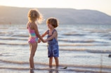 two girls standing on seashore