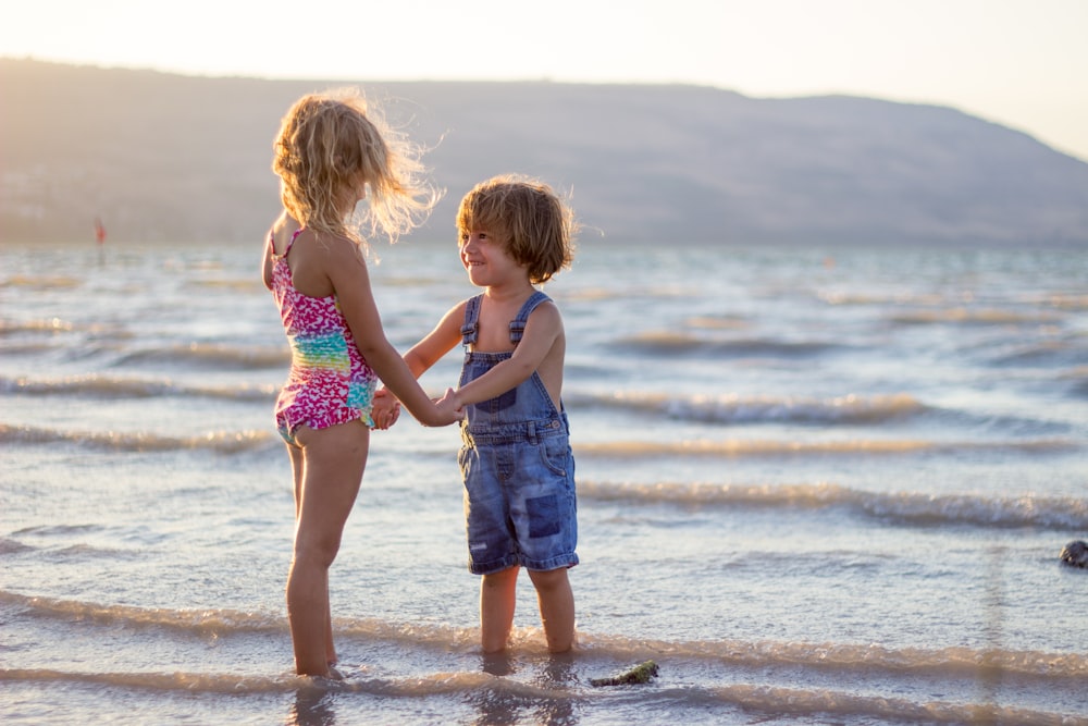 two girls standing on seashore