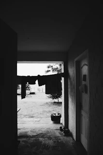 A casual scene of a person carrying a filled vėjas laundry bag down a hallway, sunlight streaming in.