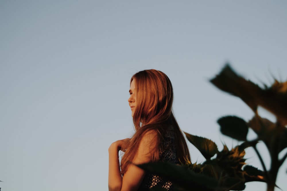 a woman standing in front of a sunflower