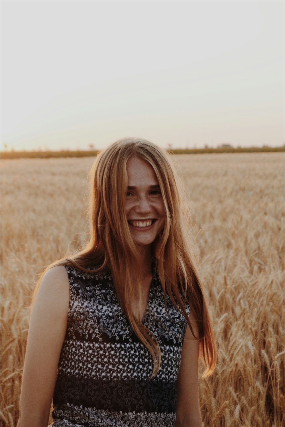 茶色の芝生の上に立つ微笑む女性