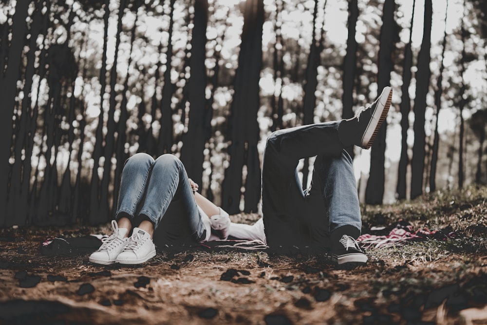 two person lying surrounded by trees