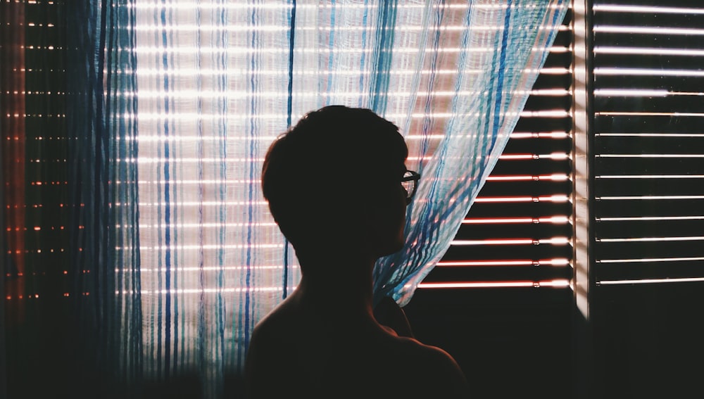 person with eyeglasses staring at opened window