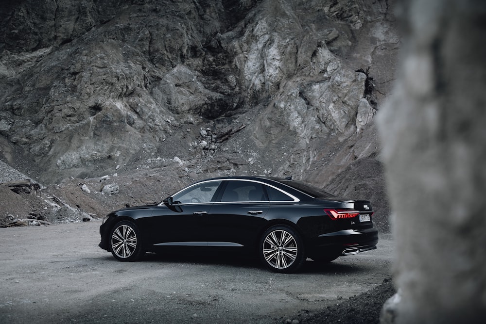 black sedan parked near gray rock formation