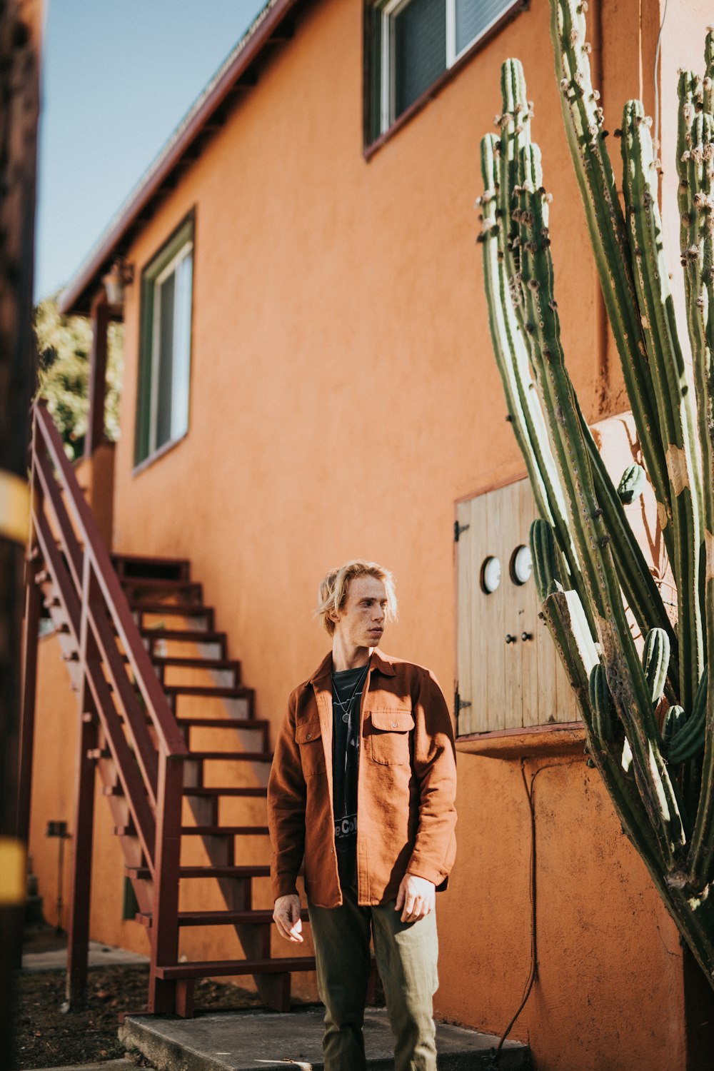 man in brown jacket standing near cactus plant during daytime