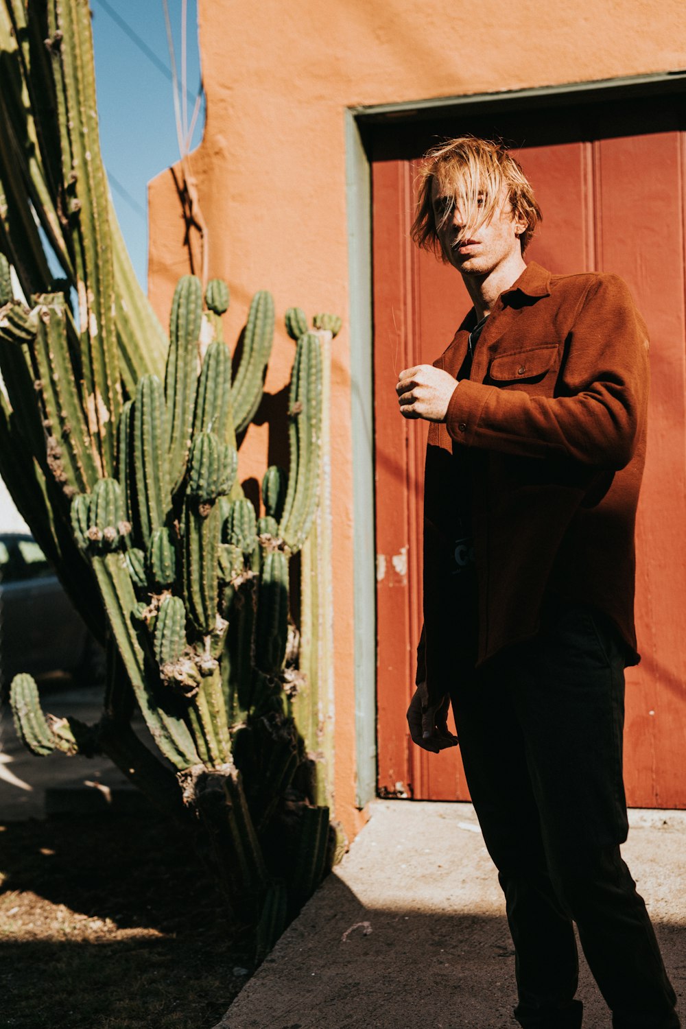 man wearing brown long-sleeved shirt near green plant