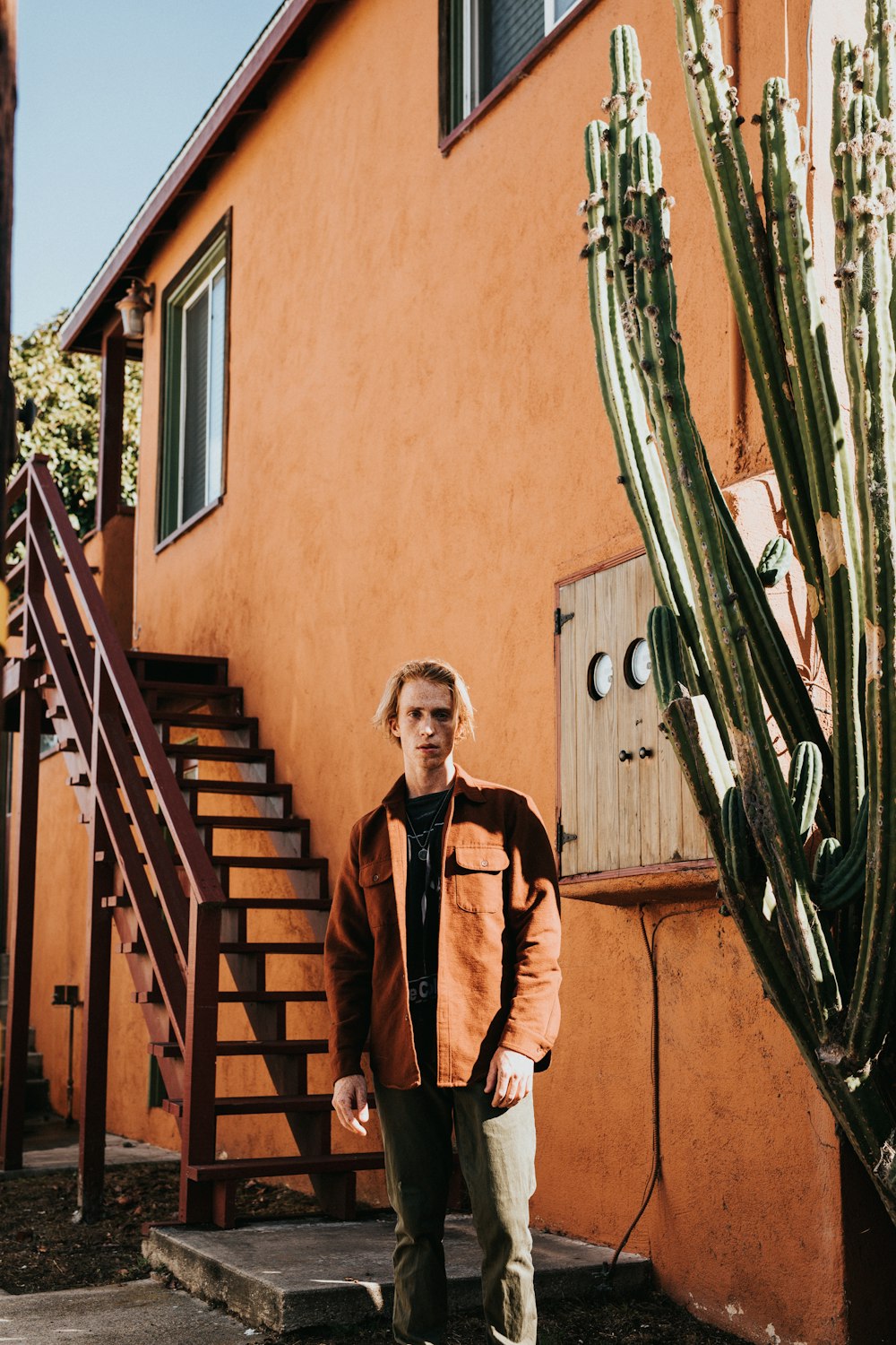 man wearing brown jacket near brown house