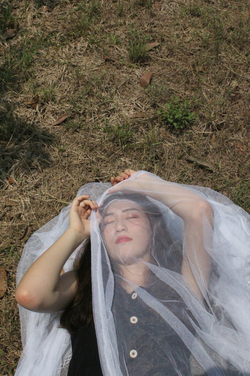 woman lying on ground covered by white mesh net