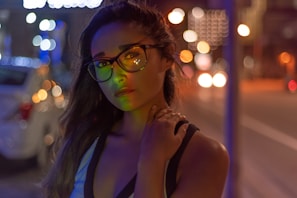 Person wearing elegant glasses outdoors with a blurred urban background.