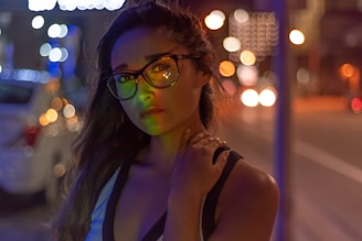 Person wearing elegant glasses outdoors with a blurred urban background.