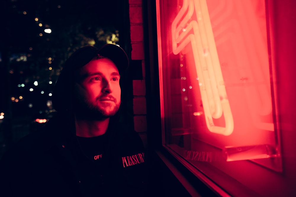 man standingnext to neon signage during night time