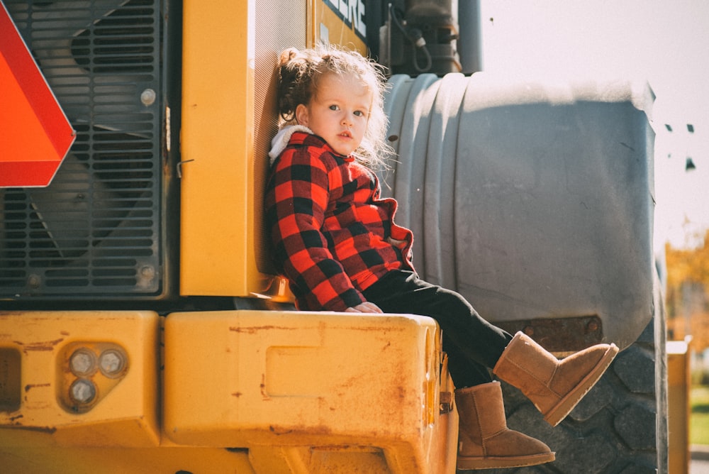 toddler girl sitting on yellow heavy equipment