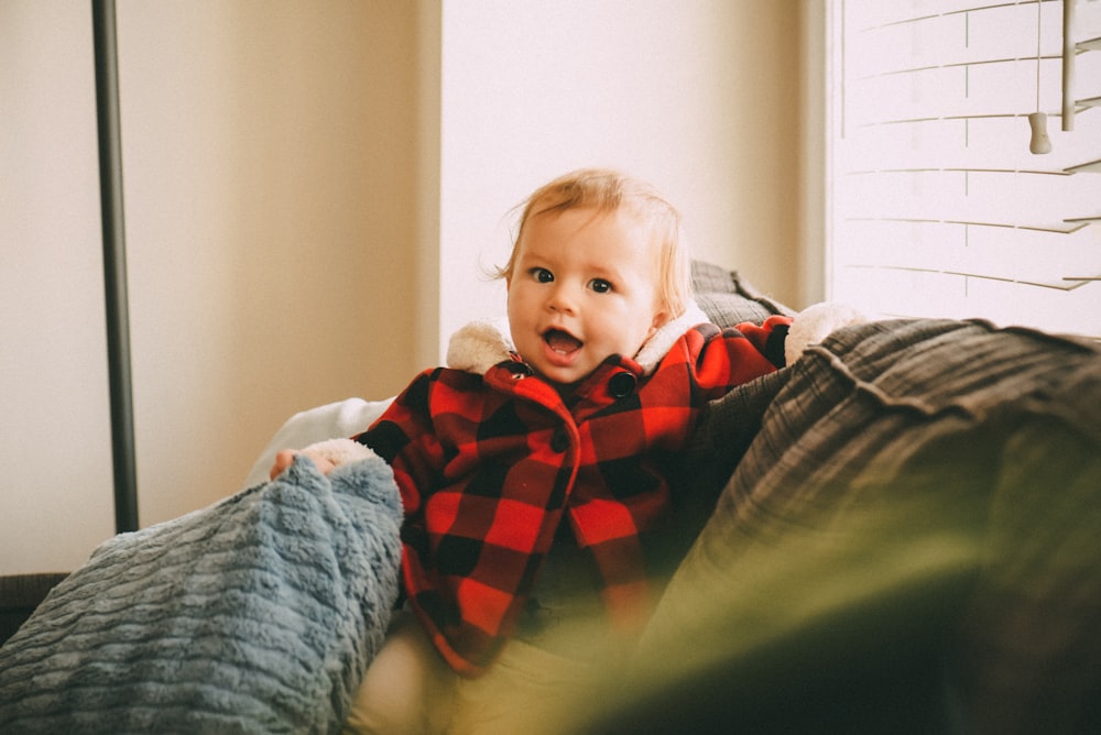 baby smiling standing on bed beside window
