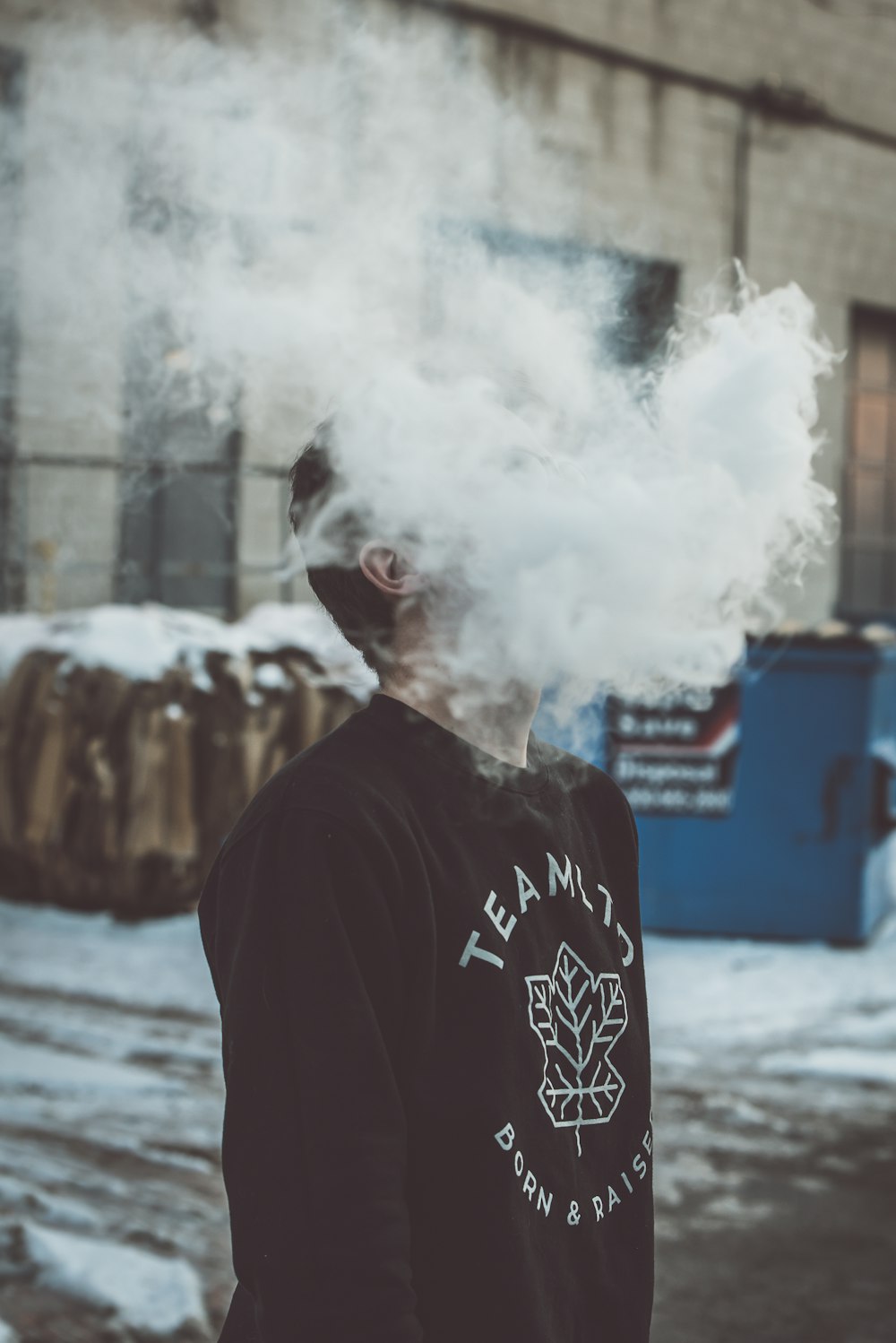 a man standing in front of a building with a cloud of smoke coming out of