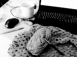 A creative workspace with yarn, hooks, and an open laptop showing the AI crochet generator.