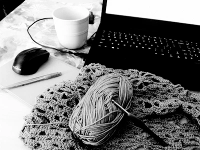 Cozy workspace with colorful yarns and a laptop displaying crochet patterns.