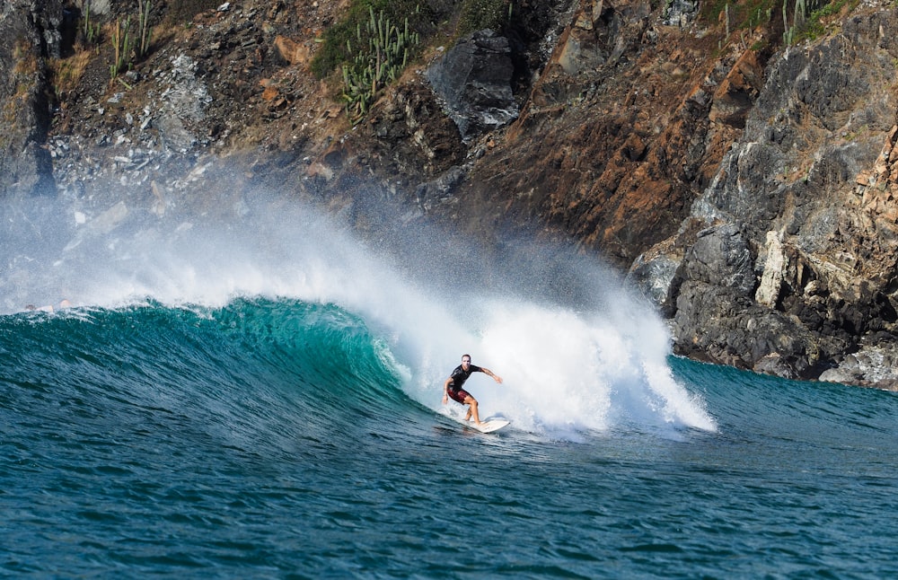 man surfboarding near rock mountain