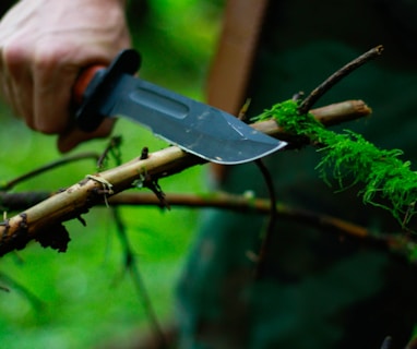 man holding hunting knife near twig