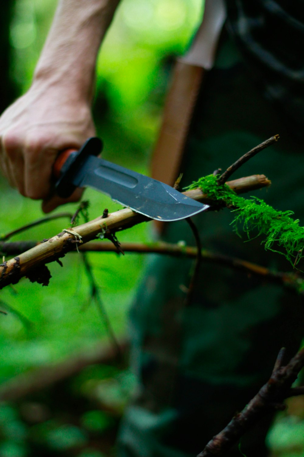 man holding hunting knife near twig