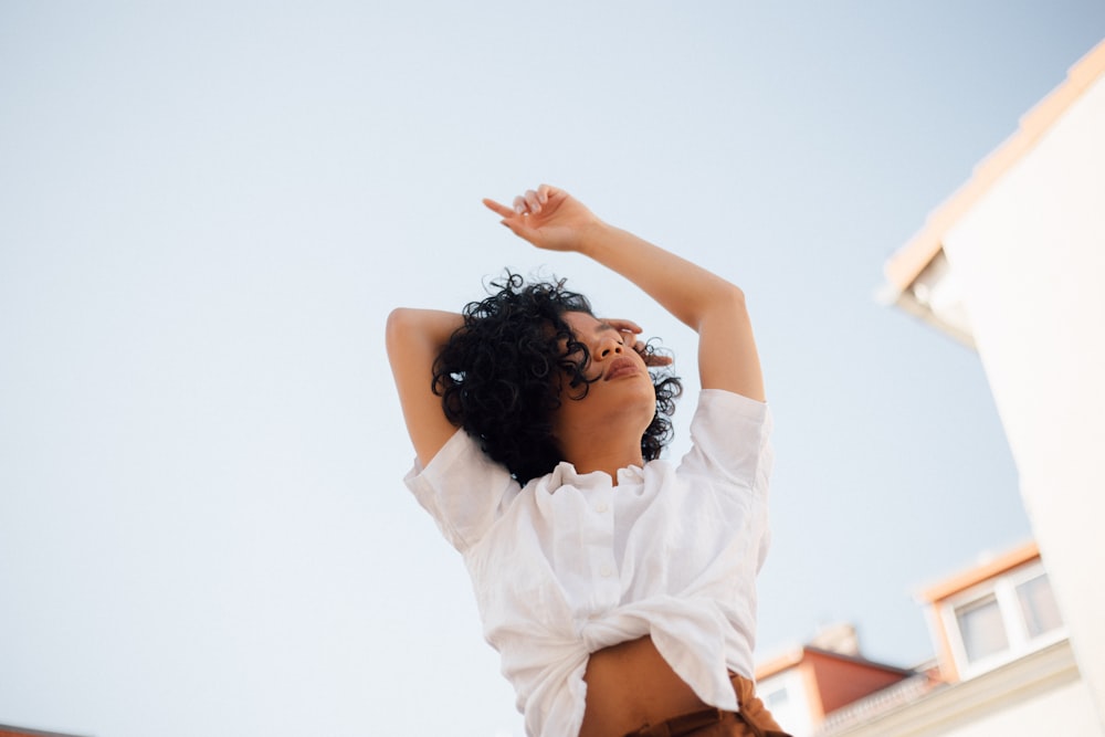 woman in whit top raising her heands