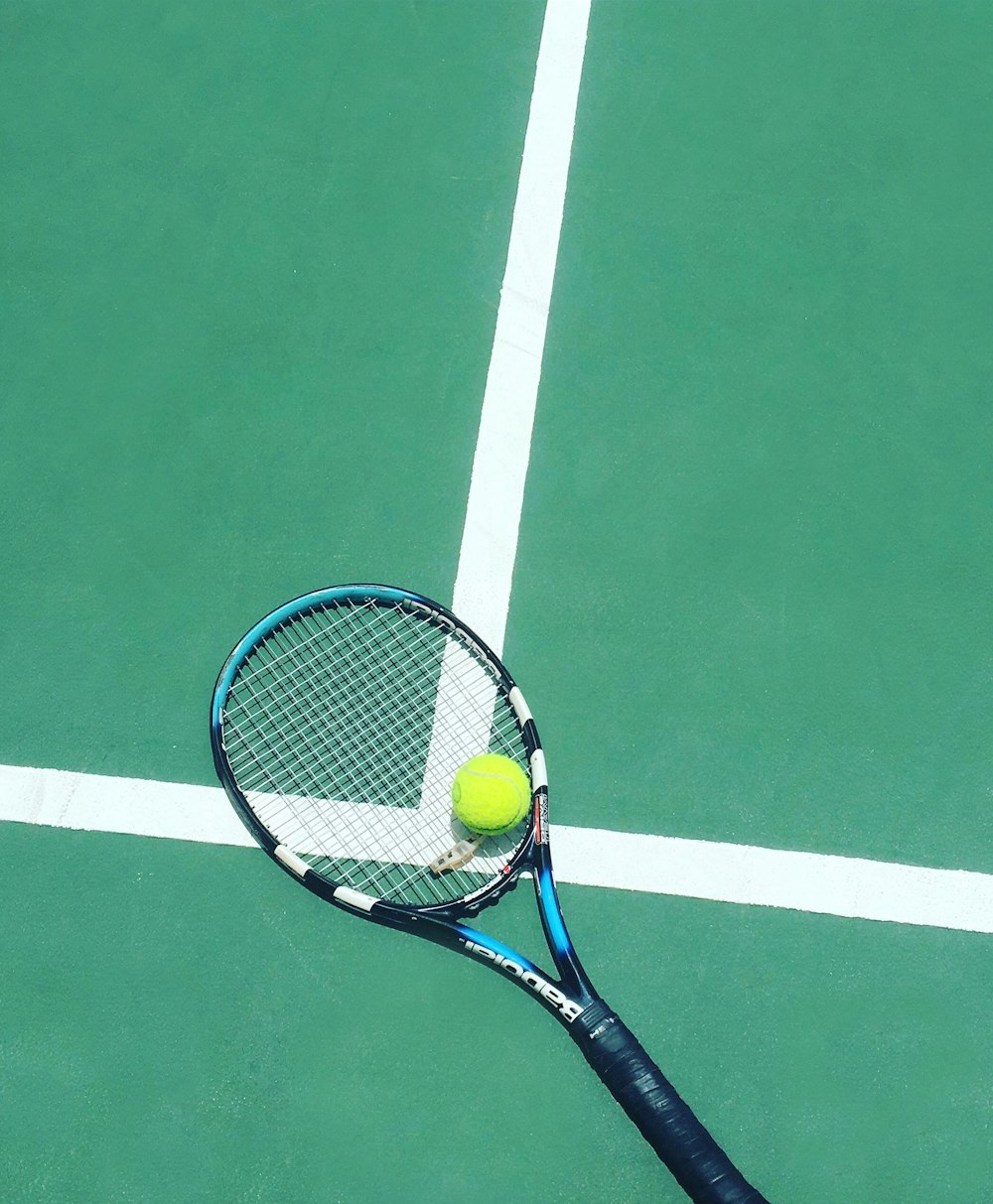 raqueta de tenis y pelota en el campo