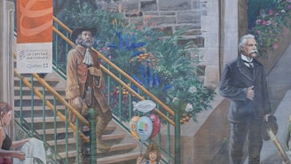 A mural features historical and modern figures in a setting with stone steps, lush greenery, and flowers. One man wears vintage clothing with a tricorn hat, while another is dressed in a suit holding a hat. A woman is shown lower down engrossed in a map or paper. Balloons and a vase with stickers add colorful elements.