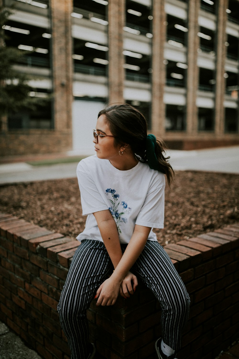 shallow focus photo of woman in white crew-neck T-shirt sitting on concrete bench