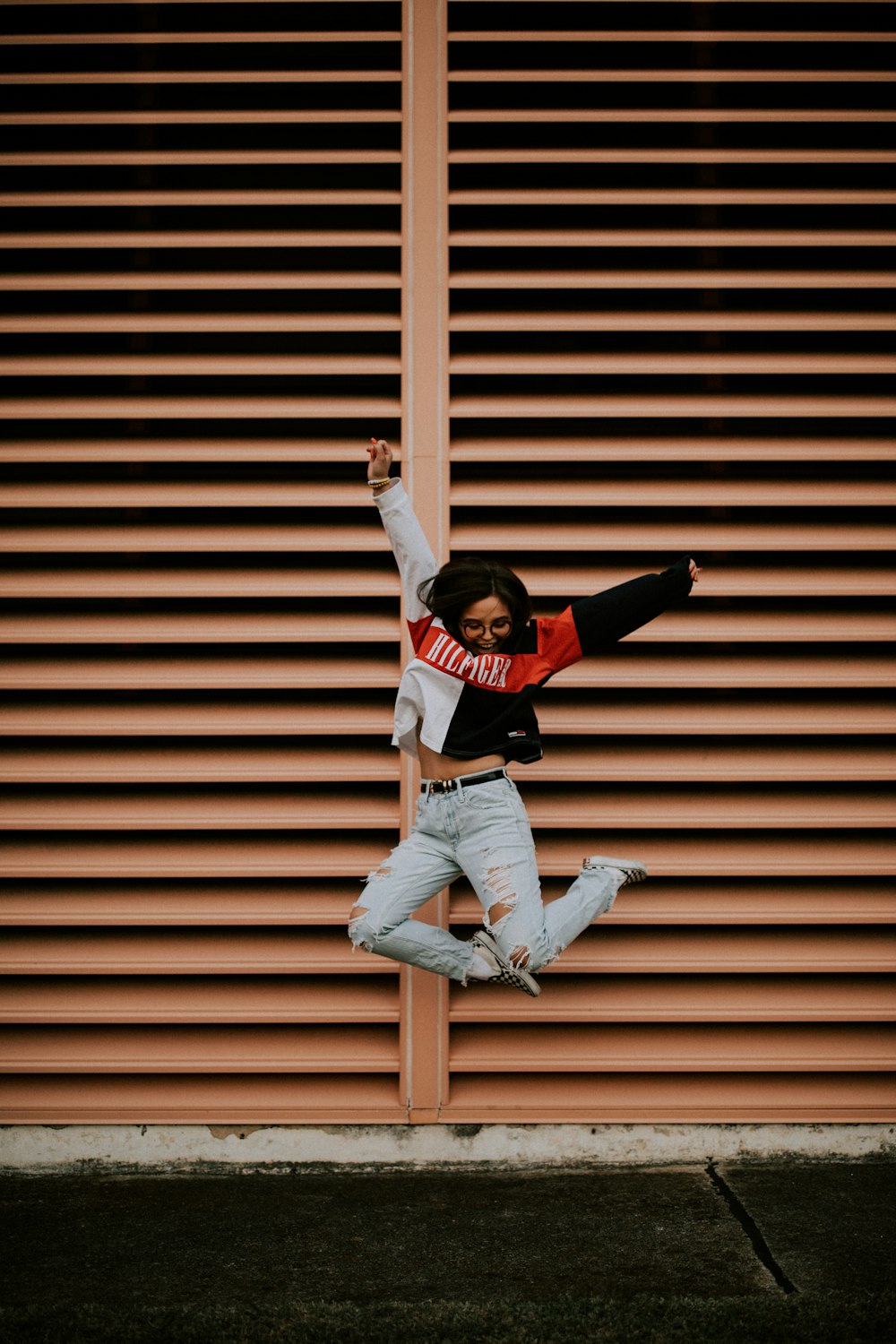 woman jumping in front of brown wall