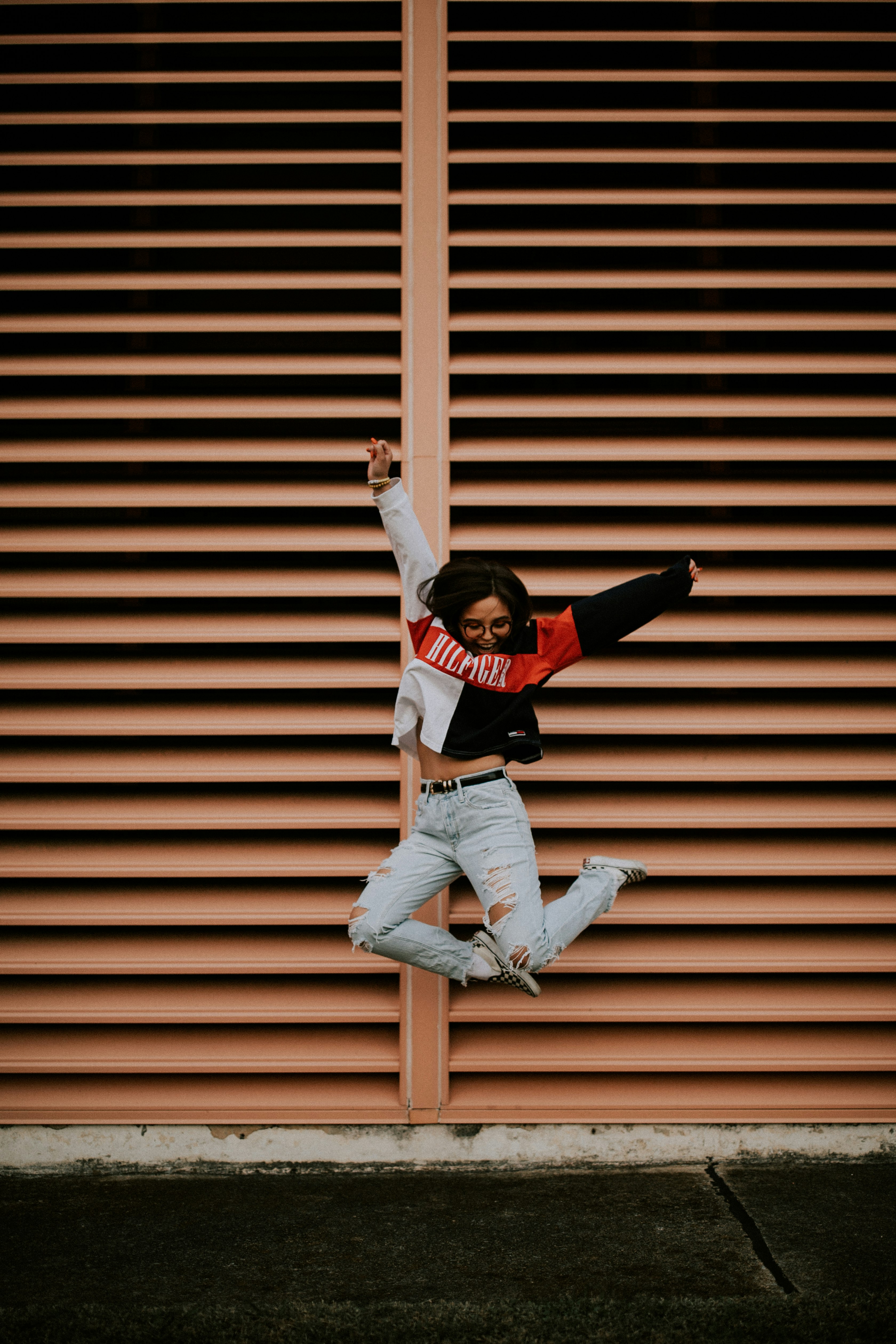 woman jumping in front of brown wall