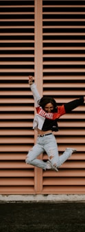 woman jumping in front of brown wall