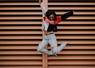 woman jumping in front of brown wall