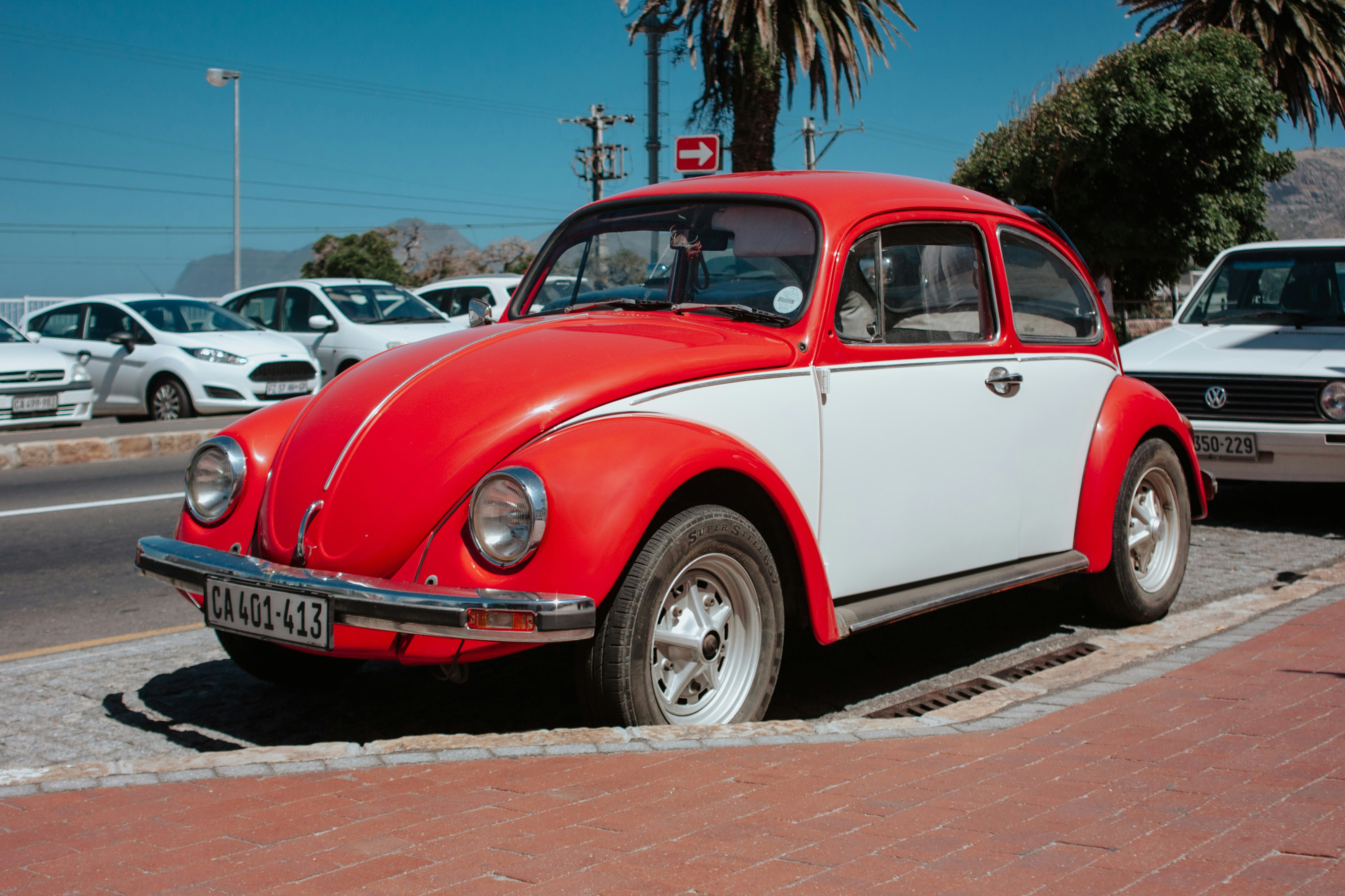 red and white Volkswagen beetle parked on side of road