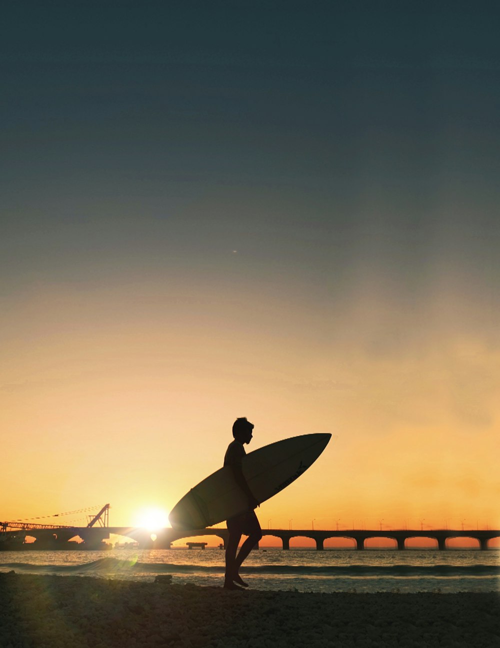 Silhouettenfotografie einer Person, die ein Surfbrett trägt