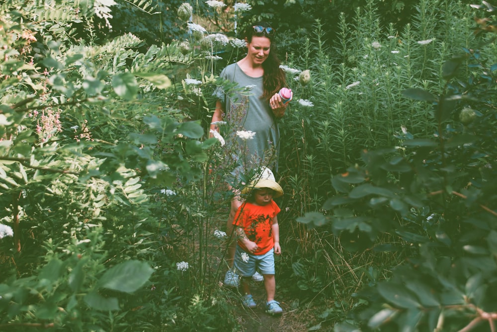 woman and child walking in flower garden during daytime